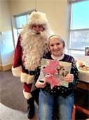 Lady smiles as she receives a door prize from Santa at The Lodge Holiday Party.