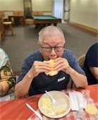 Man eating a hamburger at the AOA-Lions Picnic on August 1.