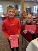 Smiling lady and young man showing homemade valentines.