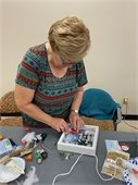 A lady working on her craft project of a winter shadow box.  