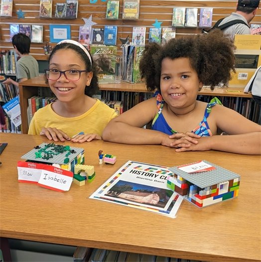 Photo of two girls playing displaying their lego creations