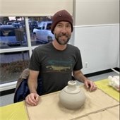 a man smiling while doing pottery