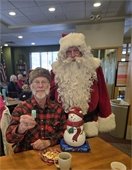 Man holds winning ticket with Santa after winning the cookie jar at the Lodge Holiday Party.e Holiday Party.