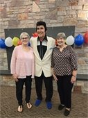 Picture of two ladies standing with Elvis in his blue suede shoes.