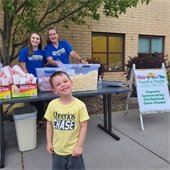 Volunteers smiling while serving popcorn to a little boy