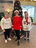 Three ladies wearing fabulous holiday sweaters in front of the tree.