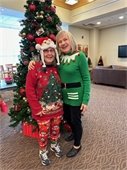 Two ladies smiling in front of the decorated tree at The Lodge.