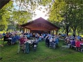 Picture of seniors sitting at tables and under the Lions Park shelter at the recent picnic.  