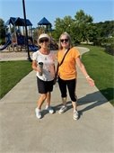 2 smiling ladies walking in the park.
