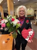 Smiling lady holding flowers and candy heart for Valentine's Day.
