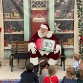 Santa reading a book to a group of young kids