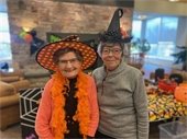 Two smiling ladies wearing witch hats.